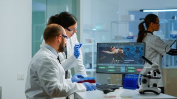 Team medical scientist conducting DNA experiments looking in computer doctors looking at medical scanner